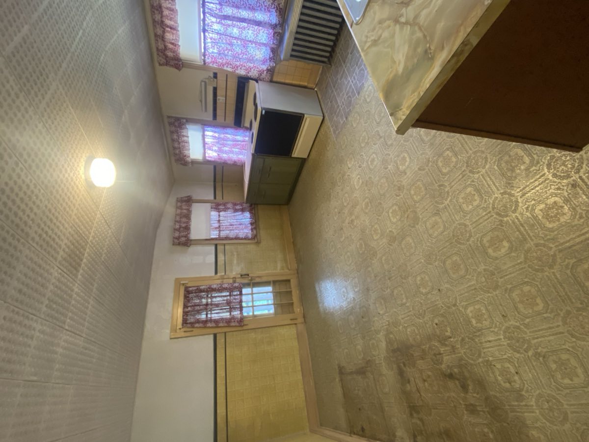 Original 1900s rowhome kitchen — tin ceiling tiles, vinyl flooring, dated cabinetry